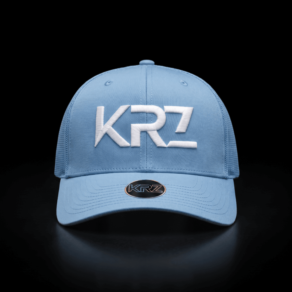 KRZ White & Black Resilient Trucker Cap featuring a structured white front, black mesh back, curved white peak and signature black KRZ shield patch. Finished with the KRZ brim badge and presented as part of the KRZ Official Resilient Collection.