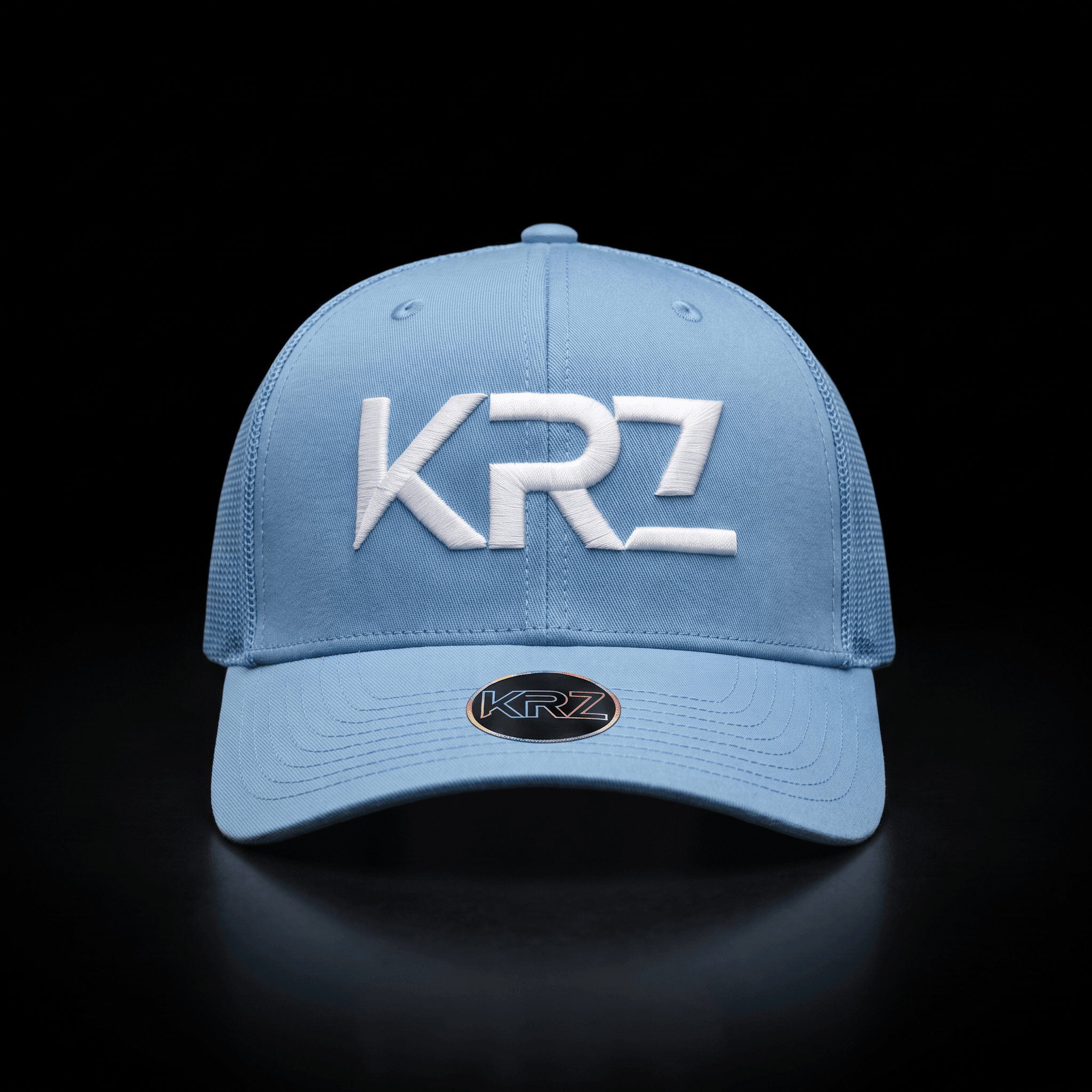 KRZ White & Black Resilient Trucker Cap featuring a structured white front, black mesh back, curved white peak and signature black KRZ shield patch. Finished with the KRZ brim badge and presented as part of the KRZ Official Resilient Collection.